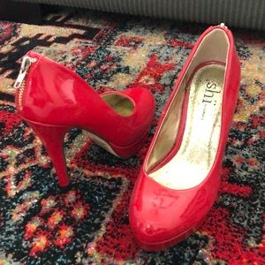 Red stiletto pumps with gold zipper